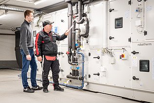 Auszubildender mit einem Kollegen in der Schaltzentrale