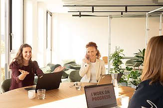 Mitarbeitende sitzen gemeinsam am Tisch uns besprechen etwas.