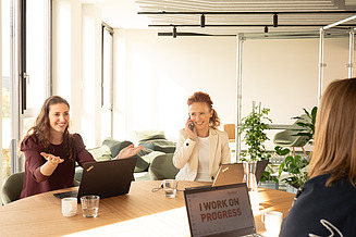 Staff members are sitting together at a table, discussing something.
