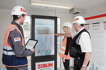 ZÜBLIN-Mitarbeiter stehen in einem Baustellencontainer vor einer Taktungstafel