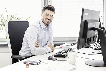 Foto von einem Mann, der im Büro vor dem Bildschirm sitzt 