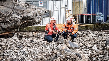 Zwei Mitarbeiter in Arbeitsschutzkleidung auf einer Baustelle