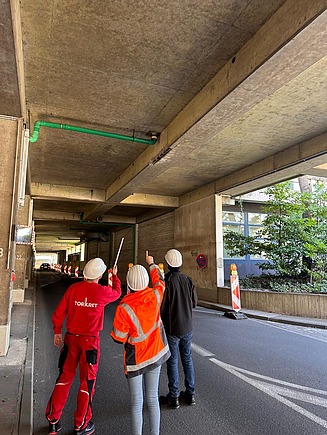 Drei Mitarbeitende schauen Richtung Decke eines Bauprojektes