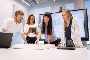 Vier ZÜBLIN-Mitarbeitende, die zusammen über einen Tisch gebeugt einen Plan besprechen.