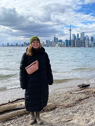 Junge Frau in Winterkleidung, im Hintergrund die Skyline von Toronto