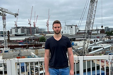 Junger Mann vor einer Baustelle.