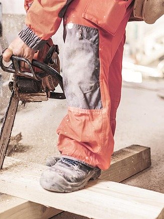 A piece of wood is being sawn using a chainsaw.