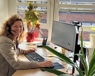 Mitarbeiterin mit Headset an einem Büroarbeitsplatz