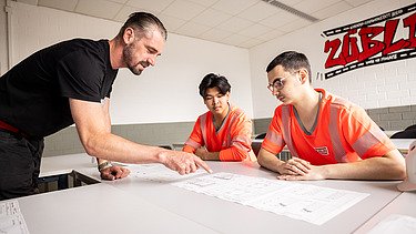 Auszubildende und Ausbilder schauen einen Plan an
