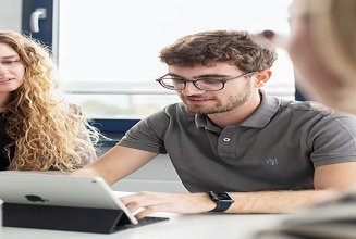 Foto von einer lächelnden Mitarbeiterin mit Bauhelm und Tablet