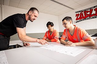Auszubildende und Ausbilder schauen einen Plan an
