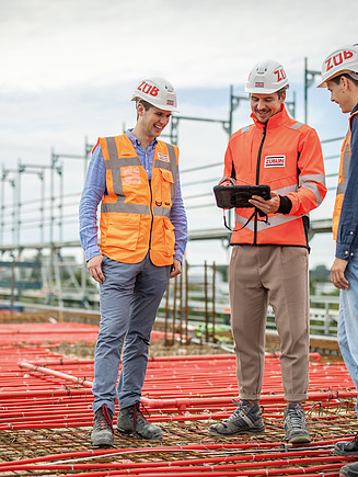Drei Mitarbeiter auf der Baustelle in einer Besprechungssituation