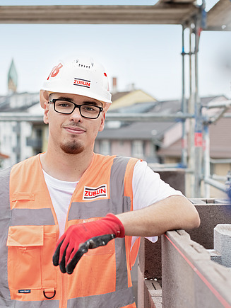 Auszubildender mit PSA auf einer Baustelle.
