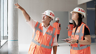 Two people are looking at a building site 