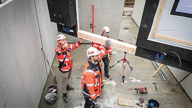 Mitarbeitende bei der Arbeit an einem Holzelement