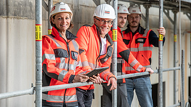 ZÜBLIN Mitarbeitende stehen in persönlicher Schutzausrüstung auf einem Baugerüst.