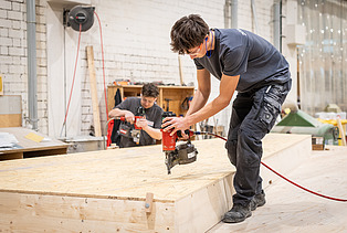 Two apprentices working on wooden components