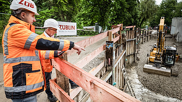 Zwei Mitarbeiter in Arbeitsschutzkleidung bei einem Rundgang über die Baustele