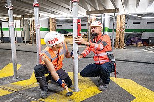 Zwei Mitarbeiter in Arbeitsschutzkleidung auf einer Baustelle