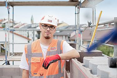 Junger Mann in Arbeitsschutzkleidung auf der Baustelle