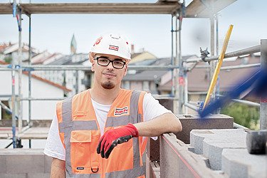 Junger Mann in Arbeitsschutzkleidung auf der Baustelle