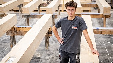 Mitarbeitender zwischen Holzelementen