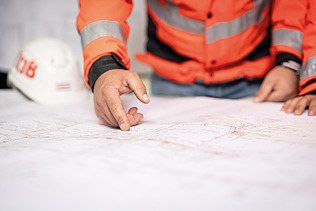 Close-up: An employee points to a building plan
