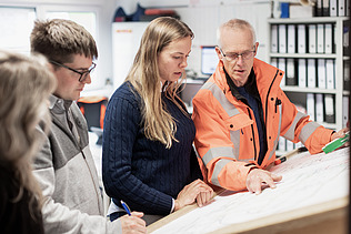 Foto von ZÜBLIN-Kolleg:innen, die gerade etwas anhand eines Bauplans besprechen