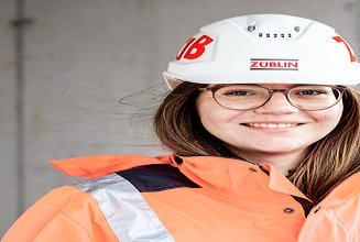 Foto von einer Frau auf der Baustelle, die in die Kamera lächelt