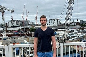 Junger Mann vor einer Baustelle.