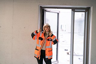 Junge ZÜBLIN Mitarbeiterin mit PSA auf einer Baustelle.