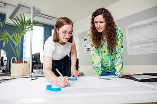 Zwei Mitarbeiterinnen besprechen einen Bauplan.