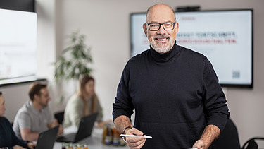 Foto eines ZÜBLIN-Kalkulators in einem Besprechungsraum, der in die Kamera lächelt.