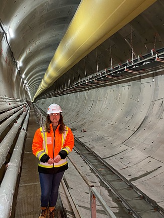 Junge Frau in Arbeitssschutzkleidung in einem Tunnel.