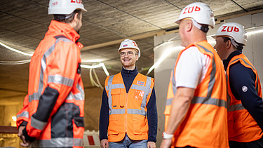 Four employees wearing high-visibility clothing at a building site, in the middle of a meeting