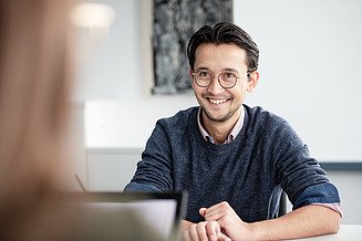 Zwei Mitarbeitende sitzen gemeinsam am Tisch und besprechen etwas.