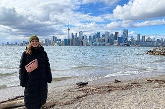 Junge Frau in Winterkleidung, im Hintergrund die Skyline von Toronto