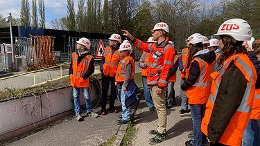 Kinder in Arbeitsschutzkleidung auf einer Baustelle