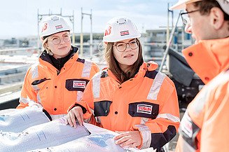 Foto von drei Personen in Schutzkleidung auf einer Baustelle