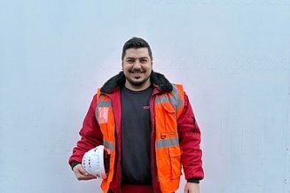 Junger Mann in Arbeitsschutzkleidung vor einer weißen Wand