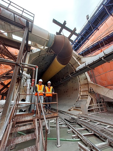 Two staff members in high-visibility clothing in front of a tunnel