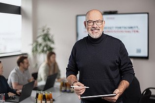 Foto eines ZÜBLIN-Kalkulators in einem Besprechungsraum, der in die Kamera lächelt.