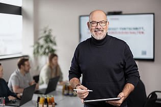 A photo of a ZÜBLIN estimator in a meeting room, smiling at the camera.
