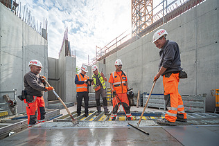 Five people in high-visibility workwear working on the building site