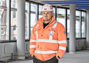 ZÜBLIN Mitarbeiter steht mit Schutzausrüstung auf Baustelle und schaut in die Kamera
