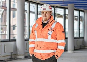 ZÜBLIN Mitarbeiter steht mit Schutzausrüstung auf Baustelle und schaut in die Kamera