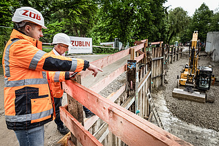Zwei Mitarbeiter in Arbeitsschutzkleidung bei einem Rundgang über die Baustele