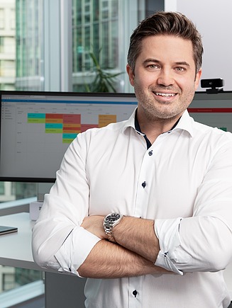 Mitarbeiter steht vor Schreibtisch.