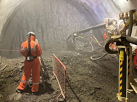 Foto eines Mitarbeiters auf einer Tunnelbaustelle neben einer Tunnelbohrmaschine.