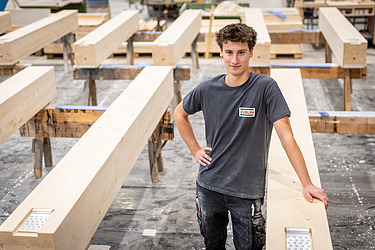 An employee leaning against wooden structures with their arms crossed